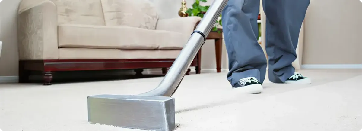 Carpet cleaning technician using a hot-water extraction wand on a light-colored carpet in a living room, Long Beach, CA.